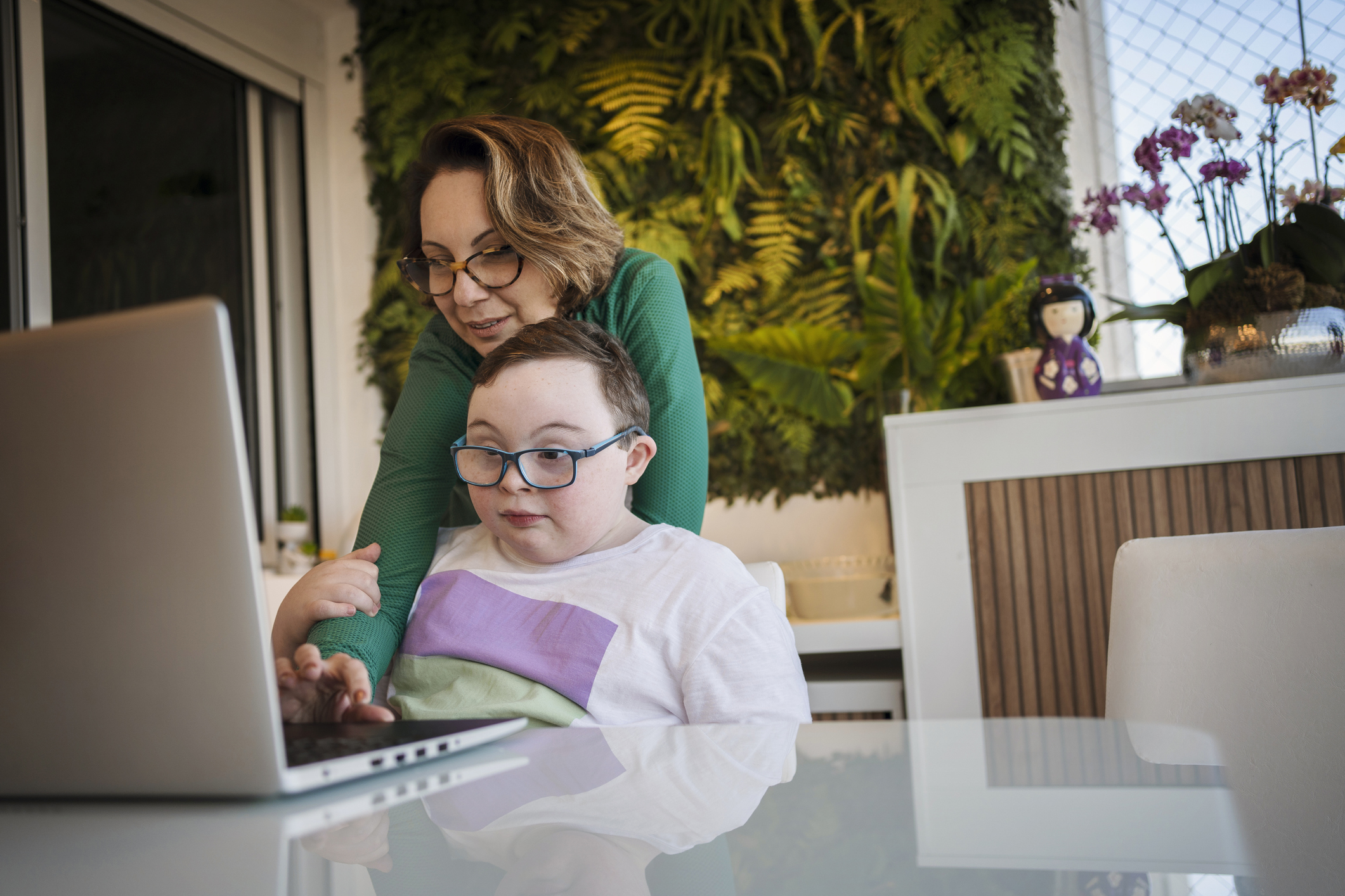 Een vrouw en een kind gebogen over een laptop.